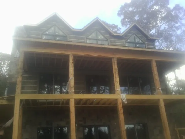 Dormers and porch framing on a large log home under construction — Roof Coating work by our crew in Bringhurst