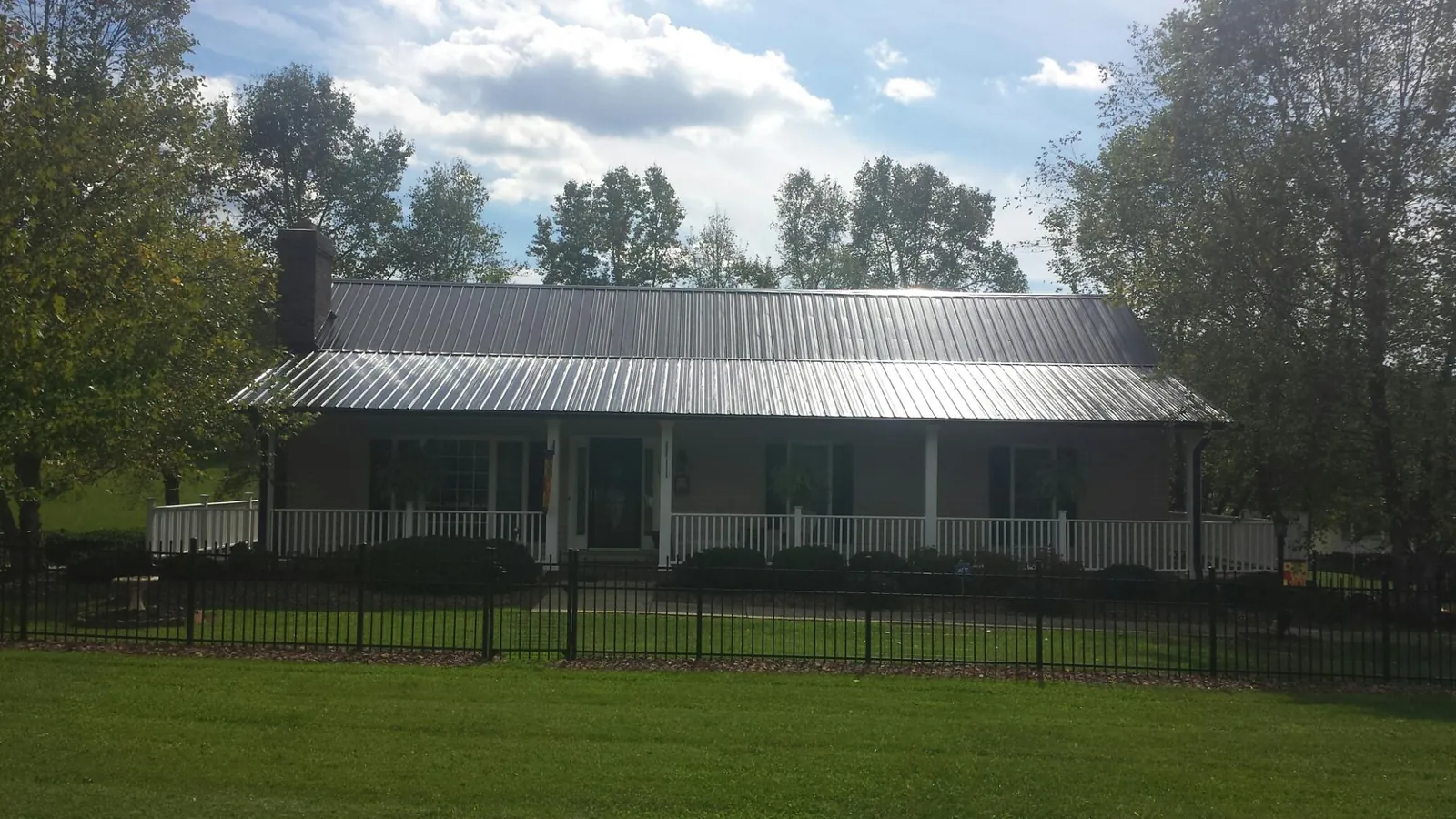 Gray metal roof on a brick ranch with a full width front porch — Gutter Guard Installation work by our crew in Bringhurst