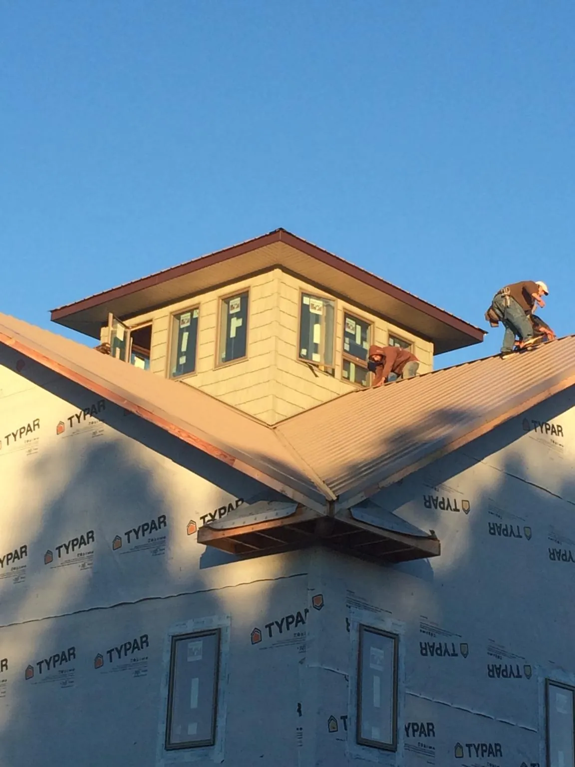 Roofers working around a rooftop cupola on a new metal roof at sunset — Roof Waterproofing in Bringhurst by Roofing Brothers